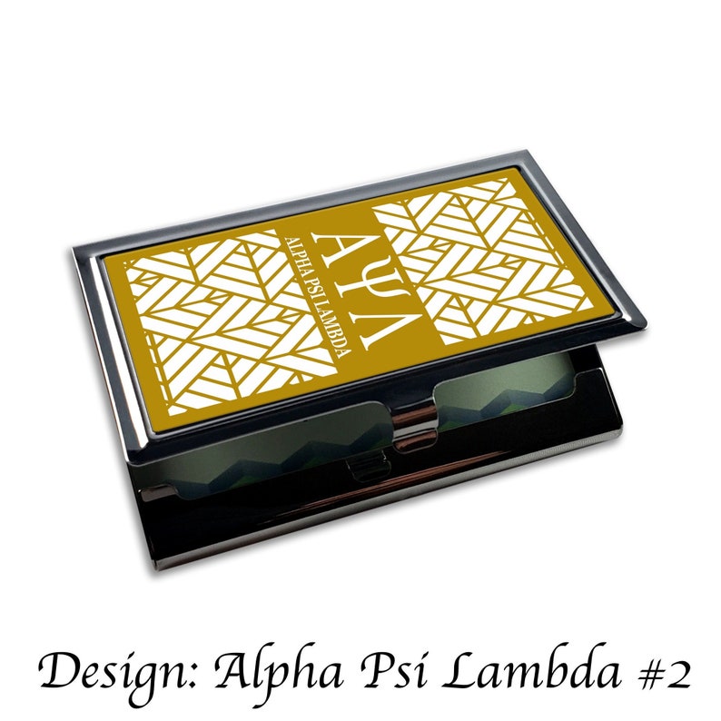Peut inclure: Un porte-cartes de visite or et blanc avec un motif g&eacute;om&eacute;trique et le texte "&Alpha;&Psi;&Lambda; Alpha Psi Lambda" sur le devant.