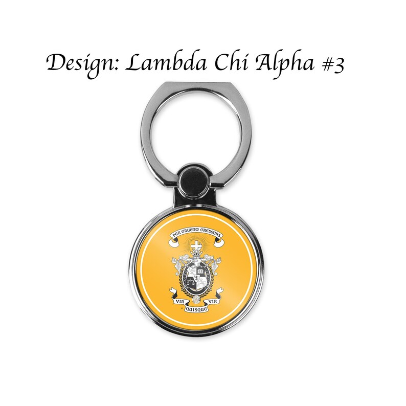 May include: A silver phone ring holder with a round, yellow, and white design. The design features a crest with a cross, a crown, and the text "For Council & Decisions".