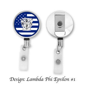 May include: A silver retractable badge holder with a blue and white American flag design featuring a crest with the text "STEMMONEL - 1913" and "ANNO DOMINI - ET IN AETERNUM".