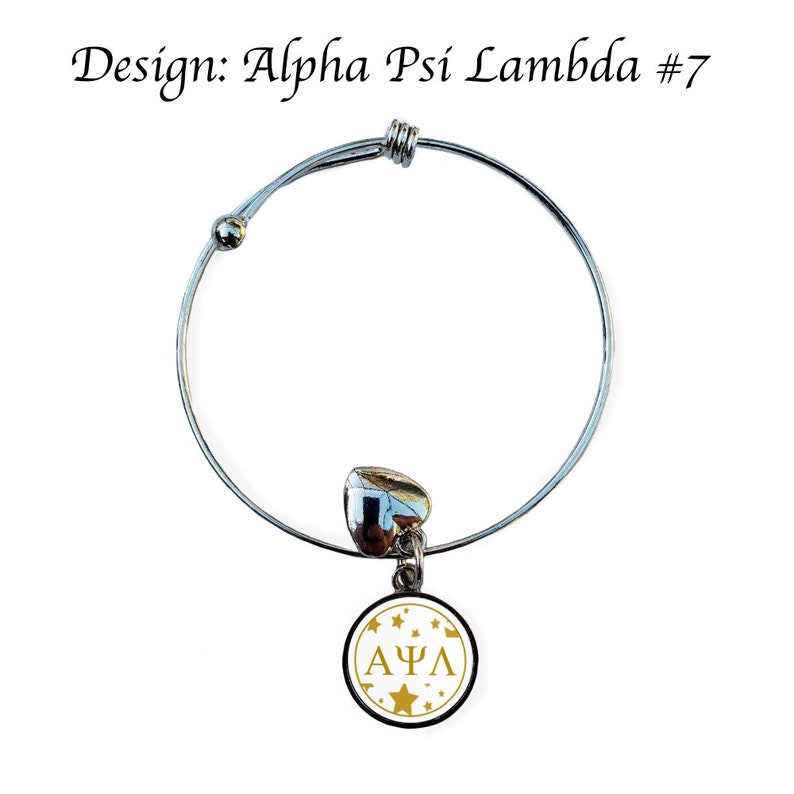 May include: A silver expandable bracelet with a charm featuring a white circle with gold stars and the letters "&Alpha;&Psi;&Lambda;" in gold.