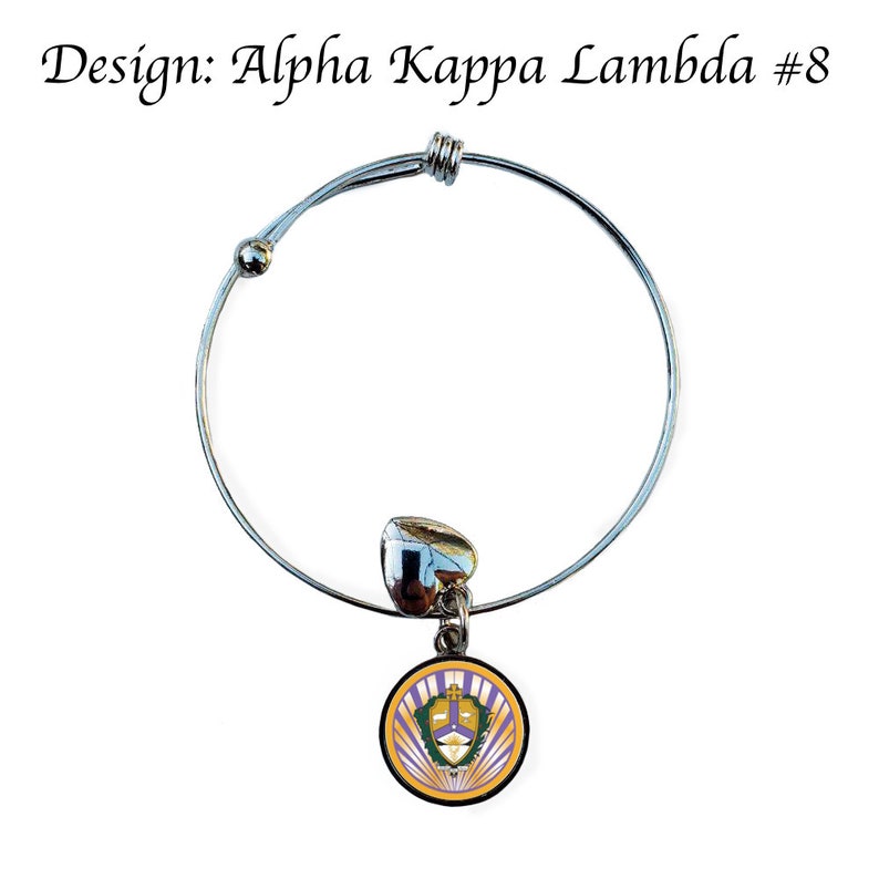 Puede incluir: Pulsera extensible de plata con un dije que presenta el escudo de la hermandad Alpha Kappa Lambda. El escudo es morado, dorado y blanco con un escudo y una corona.