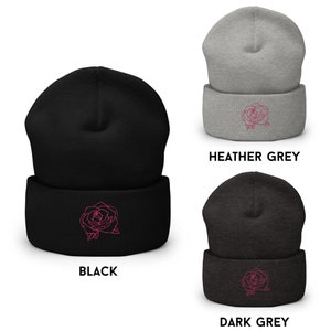 以下が含まれることがあります： ピンクのバラのデザインが施されたビーニー帽が3つ。帽子は黒、ヘザーグレー、ダークグレーです。