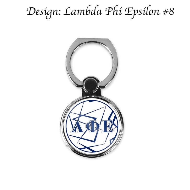 Może przedstawiać: Srebrny uchwyt do telefonu z pierścieniem, z białym k&oacute;łkiem z niebieskim i białym geometrycznym wzorem i literami "&Lambda;&Phi;&Epsilon;".