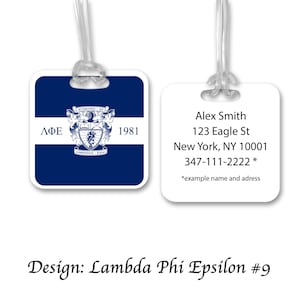 May include: Two luggage tags. One is navy blue with a white stripe and a crest, the Greek letters ΛΦΕ, and the year 1981. The other tag is white with the name Alex Smith, address, and phone number.