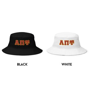 May include: Two bucket hats with the letters "A&Pi;&Gamma;" in red with a gold outline. The hat on the left is black and the hat on the right is white.