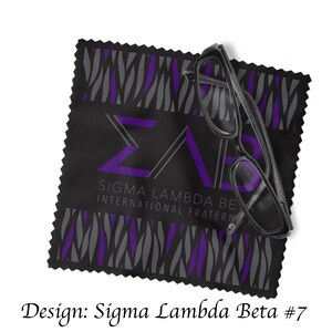 Może przedstawiać: Czarna ściereczka z mikrofibry z wzorem w pasy zebry w kolorze fioletowym i szarym. Ściereczka zawiera litery "&Sigma;&Lambda;&Beta;" w kolorze fioletowym i tekst "Sigma Lambda Beta International Fraternity".