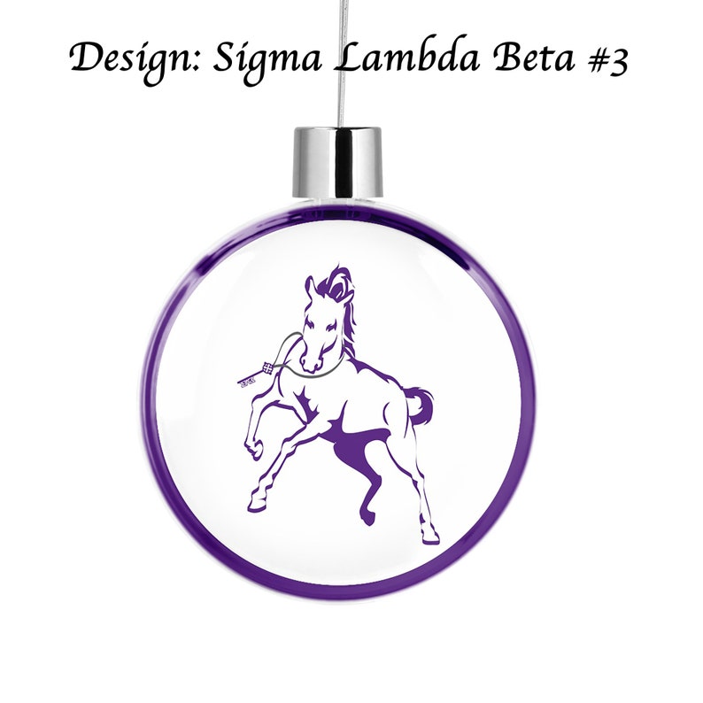 Puede incluir: Adorno navide&ntilde;o morado y blanco con una silueta de caballo morado sobre fondo blanco. El adorno tiene una parte superior plateada y una cinta morada.