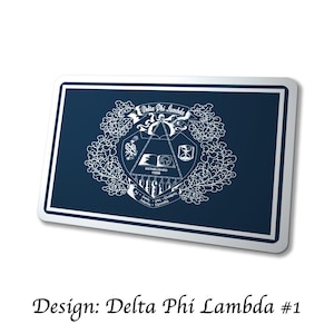 May include: A navy blue rectangular design with a white border. The design features the words "Delta Phi Lambda" in a banner, along with a crest and the text "Established 1998". The text "Design: Delta Phi Lambda #1" is at the bottom.
