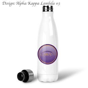May include: White stainless steel water bottle with a purple and gold circular design featuring the letters "AKA" in a stylized font.