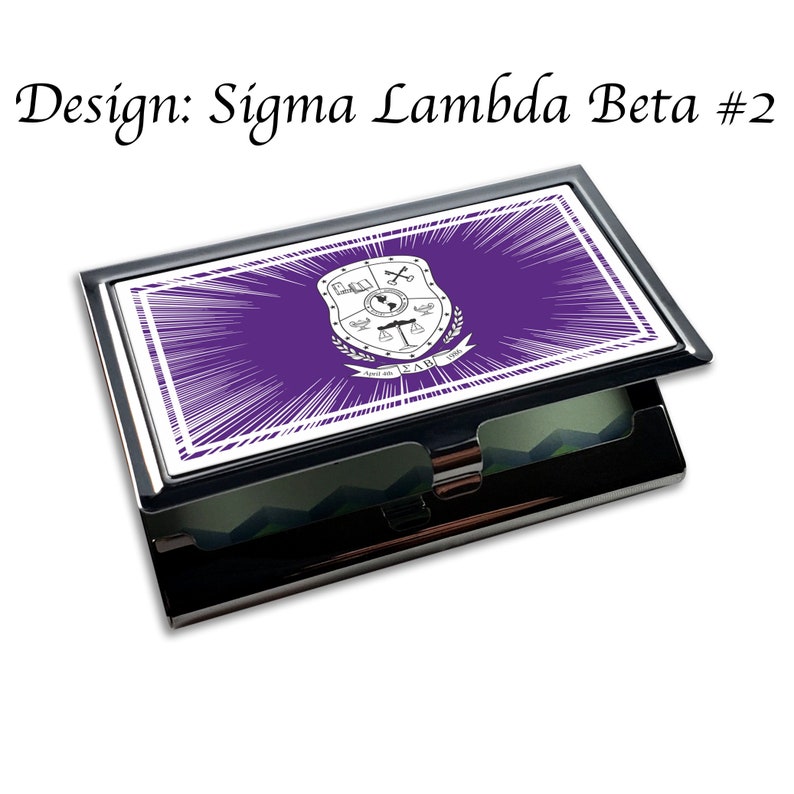 Puede incluir: Un porta tarjetas de plata con un dise&ntilde;o morado y blanco. El dise&ntilde;o presenta un escudo con las letras "&Sigma;&Lambda;&Beta;" y el texto "April 26, 1900".