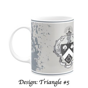May include: White ceramic mug with a gray and white design. The mug features a crest with a triangle and the words "Veritas Omnia Vincit". The design includes gray paint splatters and the text "Design: Triangle #5".