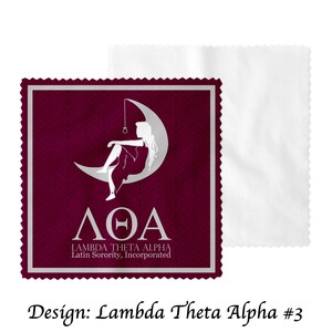 May include: A burgundy square microfiber cleaning cloth with a silver border and a white design of a woman sitting on a crescent moon. The text "&Lambda;&Theta;&Alpha;" is below the moon and the text "LAMBDA THETA ALPHA Latin Sorority, Incorporated" is below that.