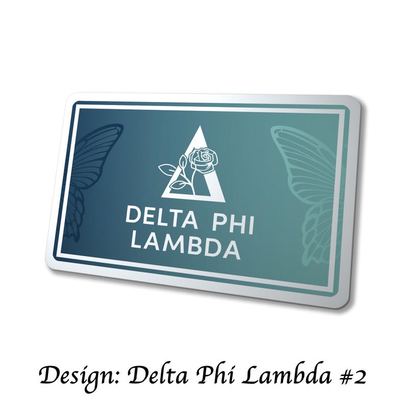 May include: A rectangular sticker with a white border and a gradient teal background. The sticker features a white triangle with a rose and the text "DELTA PHI LAMBDA". Butterfly wing outlines are on each side. The text "Design: Delta Phi Lambda #2" is below.