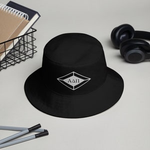 May include: Black bucket hat with a white diamond-shaped patch embroidered with the Greek letters "AΔΠ".