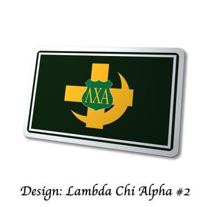 May include: A rectangular sign with a dark green background and a white border. The sign features a gold cross and crescent design, with a green shield containing the Greek letters &Lambda;XA. The text "Design: Lambda Chi Alpha #2" is at the bottom.