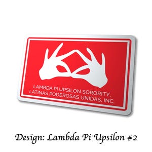 Op de afbeelding: Een rechthoekige sticker met een rode achtergrond en witte rand. De sticker toont witte handgebaren die een ruit vormen, met de tekst "LAMBDA PI UPSILON SORORITY, LATINAS PODEROSAS UNIDAS, INC." Het ontwerp is gelabeld "Lambda Pi Upsilon #2."