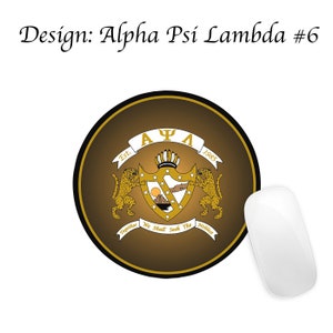 May include: A round brown mouse mat with a gold crest featuring the letters "A&Psi;&Lambda;" and the text "Est. 1985" and "Together We Shall Seek The Noblest".