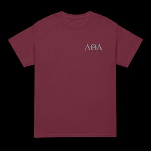 Peut inclure: Un t-shirt bordeaux avec un motif de lettres grecques blanches qui lit "AOA".
