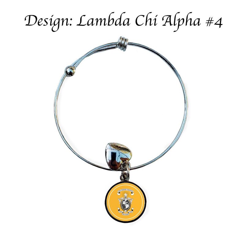 Puede incluir: Un brazalete extensible de plata con un dije en forma de c&iacute;rculo amarillo con borde negro y un escudo blanco. El escudo incluye una estrella, un coraz&oacute;n y el texto "Lambda Chi Alpha".