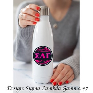 Puede incluir: Botella de agua de acero inoxidable blanca con un diseño circular negro y rosa con las letras griegas "ΣΛΓ".