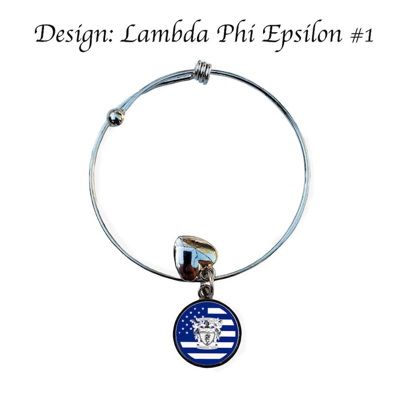 May include: A silver expandable bracelet with a charm featuring a blue and white flag with a crest in the centre. The charm is round and has a silver border. The bracelet is designed for Lambda Phi Epsilon #1.