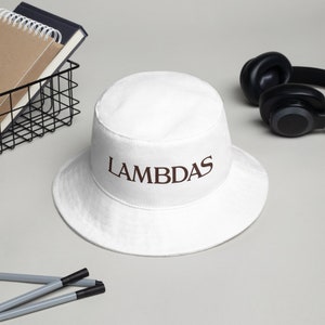 May include: White bucket hat with the word "LAMBDAS" embroidered in brown on the front.