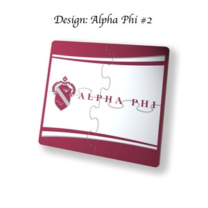 Könnte beinhalten: Ein rotes und weißes Puzzle mit den Worten "ALPHA PHI" in silbernen Buchstaben. Das Puzzle zeigt ein Wappen mit einem roten und weißen Schild und einem silbernen Vogel.