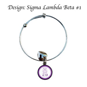 K&ouml;nnte beinhalten: Ein silbernes, ausziehbares Armband mit einem Herz-Anh&auml;nger und einem runden Anh&auml;nger mit dem Logo der Sorority Sigma Lambda Beta in Lila und Wei&szlig;.