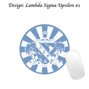 Op de afbeelding: Een ronde muismat met een blauw en wit ontwerp met tekst en een wapen. De tekst luidt "Design: Lambda Sigma Upsilon #1", en het wapen bevat de woorden "Latinos Siempre Unidos". Een witte computermuis staat naast de muismat.