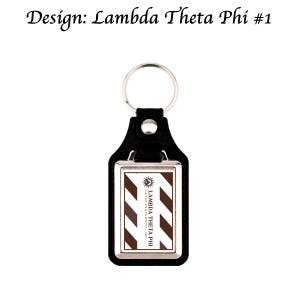 Op de afbeelding: Zwarte leren sleutelhanger met een zilverkleurig metalen frame. De rechthoekige inzet heeft bruine en witte diagonale strepen en de tekst "LAMBDA THETA PHI LATIN FRATERNITY, INC.". Het ontwerp bevat ook de tekst "Design: Lambda Theta Phi #1".