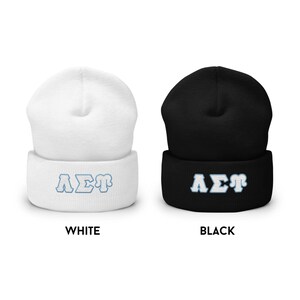 May include: Two knit beanies, one white and one black, with the Greek letters "A&Sigma;&Gamma;" embroidered in blue on the front.