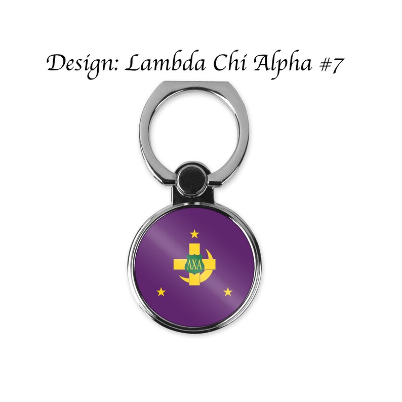 May include: A silver phone ring holder with a purple circle featuring a gold cross and crescent moon with the letters "AXA" inside. There are five gold stars around the circle. The design is labelled "Lambda Chi Alpha #7".