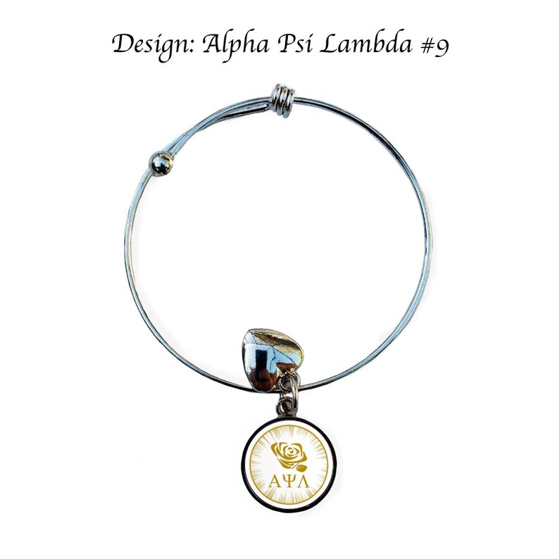 May include: A silver expandable bracelet with a charm featuring a white circle with a gold rose and the letters "&Alpha;&Psi;&Lambda;" in gold.