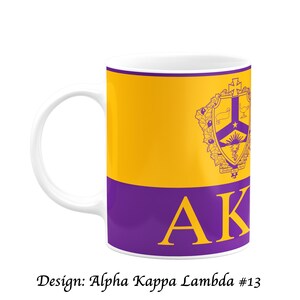 May include: White ceramic mug with a yellow and purple design. The mug features the Greek letters AK in gold, and a crest with a star and sunburst. The text "Design: Alpha Kappa Lambda #13" is at the bottom.