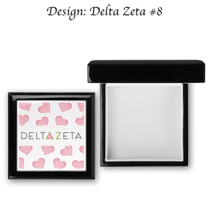 May include: Black wooden box with a hinged lid. The lid features a white background with a pink heart pattern and the text "DELTA ZETA".