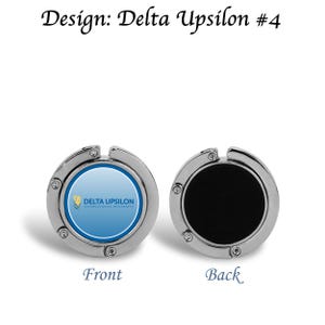 May include: A silver-colored purse hook with a round design. The front features a blue and white logo with the text "DELTA UPSILON INTERNATIONAL FRATERNITY." The back is black. The text "Design: Delta Upsilon #4" is at the top.
