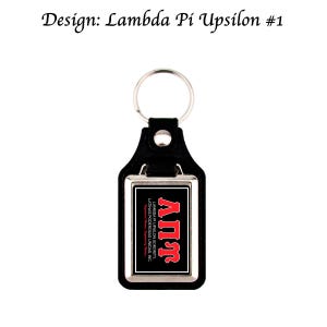 Op de afbeelding: Zwarte leren sleutelhanger met een zilverkleurig metalen frame. De sleutelhanger toont de Griekse letters ΑΠΥ in rood op een zwarte achtergrond. De tekst "LAMBDA PI UPSILON SORORITY, LATINAS PODEROSAS UNIDAS, INC" is ook zichtbaar.