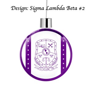 Puede incluir: Adorno navide&ntilde;o morado y blanco con fondo blanco y un c&iacute;rculo morado en el centro. El c&iacute;rculo presenta un escudo con un libro, llaves, un globo terr&aacute;queo, una balanza y dos l&aacute;mparas. El texto "April 4th", "&Sigma;&Lambda;&Beta;" y "1986" est&aacute; impreso debajo del escudo.