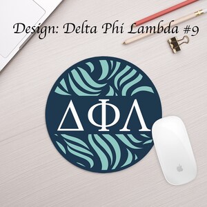 Może przedstawiać: Okrągła podkładka pod mysz z niebieskim tłem i wzorem turkusowych zwoj&oacute;w. Litery "&Delta;&Phi;&Lambda;" są białe i znajdują się w środku podkładki.
