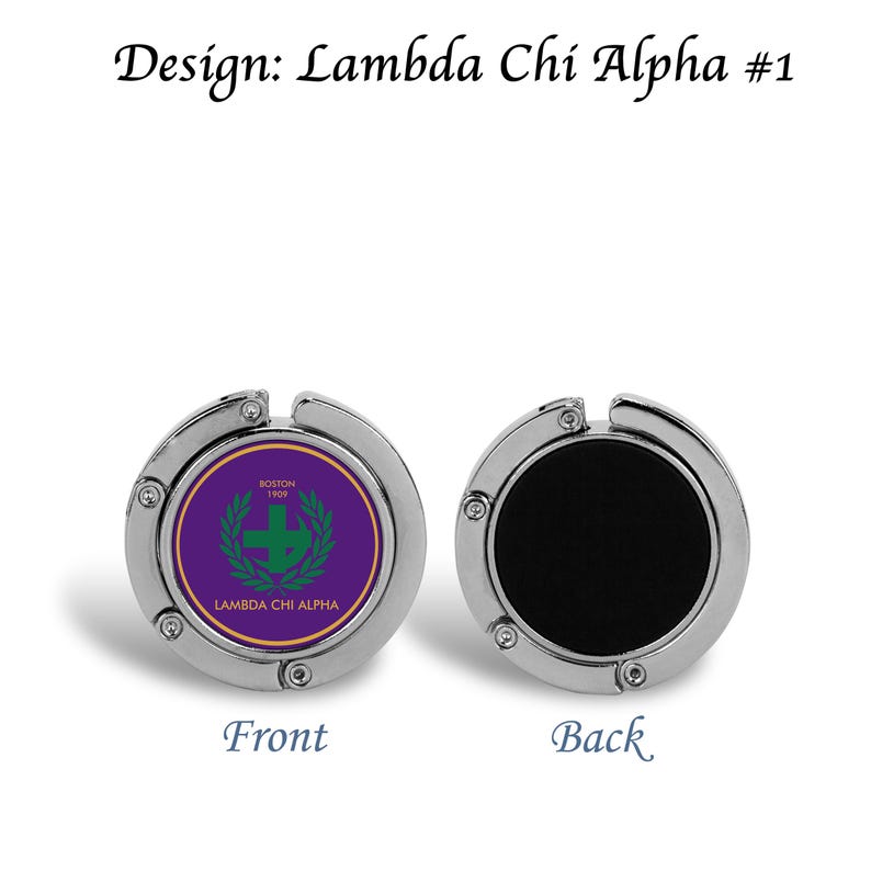 以下が含まれることがあります： 紫と緑のエンブレムが付いたシルバーカラーのバッグフック。エンブレムには十字と「Lambda Chi Alpha」と「Boston 1909」の文字が描かれています。フックの裏側は黒色です。「Front」と「Back」の文字が下にあります。