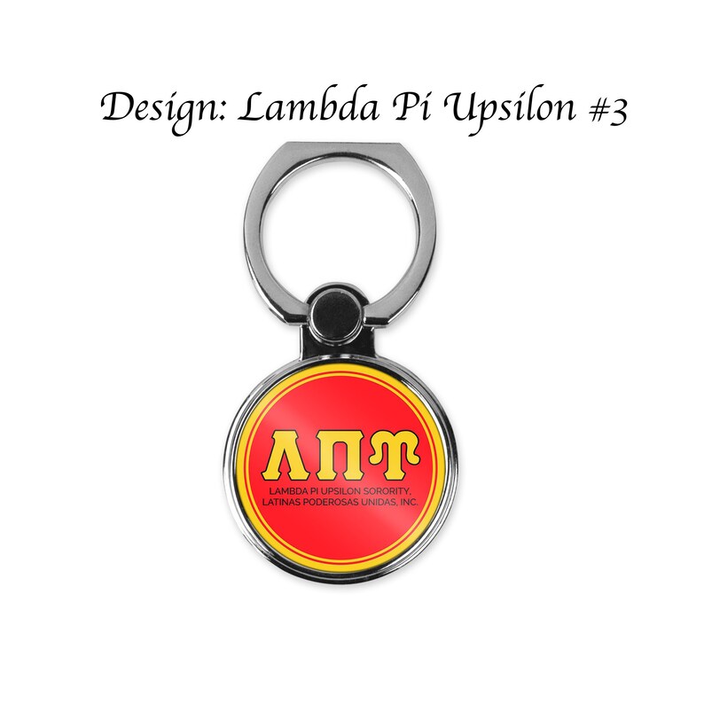 Op de afbeelding: Een zilveren telefoonringhouder met een rode en gele cirkel. De cirkel bevat de letters "&Lambda;&Pi;&Upsilon;" in geel en de tekst "LAMBDA PI UPSILON SORORITY, LATINAS PODEROSAS UNIDAS, INC." in zwart.