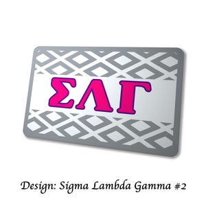 以下が含まれることがあります： グレーのひし形模様と、紫色の縁取りのある鮮やかなピンク色のギリシャ文字&Sigma;&Lambda;&Gamma;が特徴の、長方形の銀色のアイテム。「Design: Sigma Lambda Gamma #2」の文字が下部にあります。
