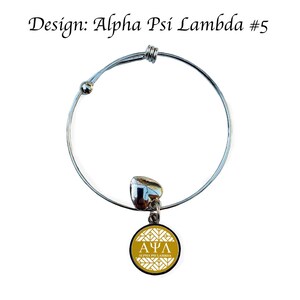 May include: A silver expandable bracelet with a charm featuring a gold circle with a white Greek letter design and the text "Alpha Psi Lambda".