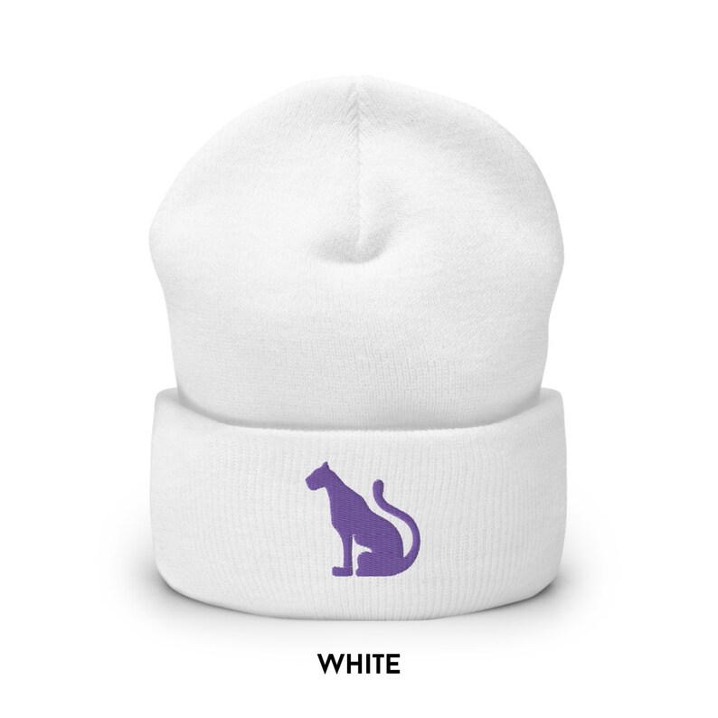 以下が含まれることがあります： 紫色の刺繍で座っているパンサーのシルエットが施された白いビーニー