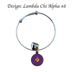 Puede incluir: Un brazalete extensible de plata con un dije que presenta el s&iacute;mbolo de la fraternidad Lambda Chi Alpha. El dije es redondo y tiene un fondo morado con una cruz dorada y una luna creciente.