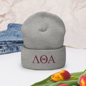 May include: Gray beanie with a maroon embroidered Greek letter design that reads "ΛΘΑ".