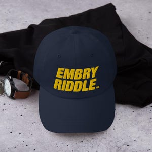 May include: A navy blue baseball cap with a yellow embroidered logo that says "EMBRY RIDDLE™".