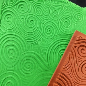 May include: A green silicone stamp with a swirling pattern, and a brown silicone stamp with a similar swirling pattern.