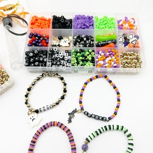 May include: A clear plastic storage box filled with various Halloween-themed beads, charms, and letters. The box includes black, white, green, purple, orange, and gold beads, as well as ghost, bat, and heart charms. The letters spell out "BOO" and "SPOOKY".