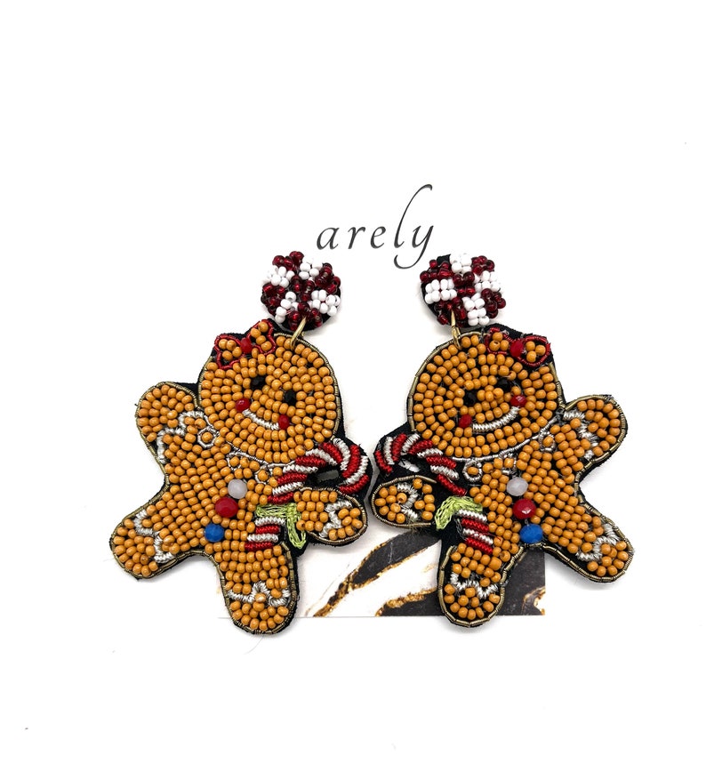 May include: A pair of gingerbread man earrings made of colorful beads. The earrings are a festive holiday accessory.
